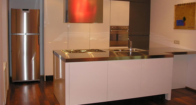 Kitchen cabinets in white high-gloss lacquer with an island and stainless steel top